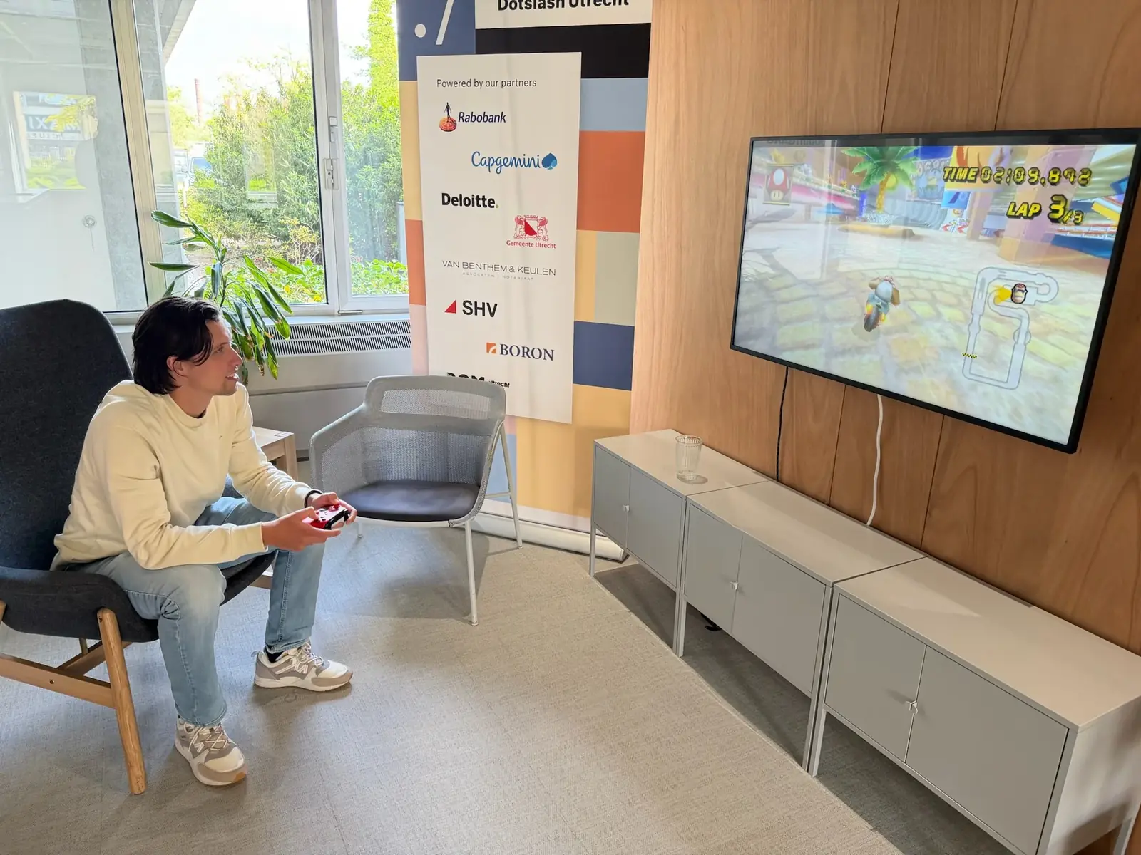 Iemand speelt Mario Kart Wii in de lobby van Dotslash Utrecht